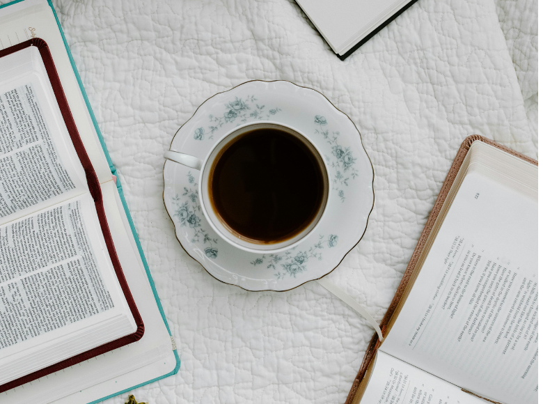 Open bibles with a cup of coffee on a tablecloth for study