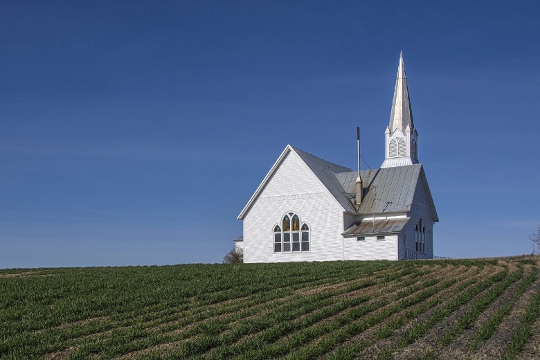 white church and steeple in a field