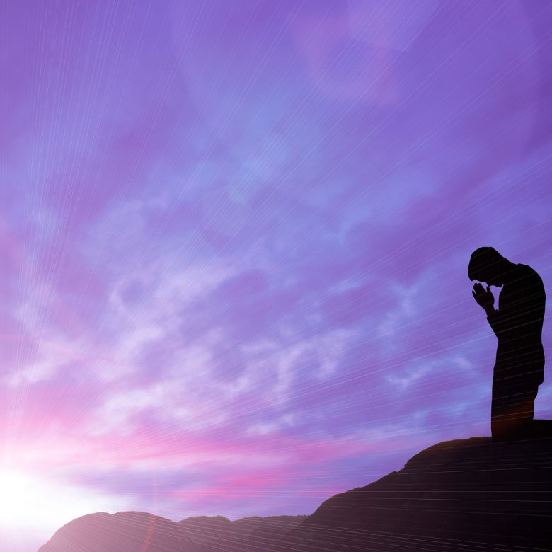 A man praying at sunrise.