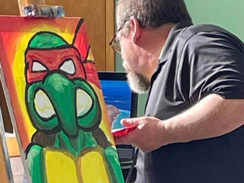 Photo of the author speed painting a Ninja Turtle for a school assembly taken by Pastor Chuck Kieffer