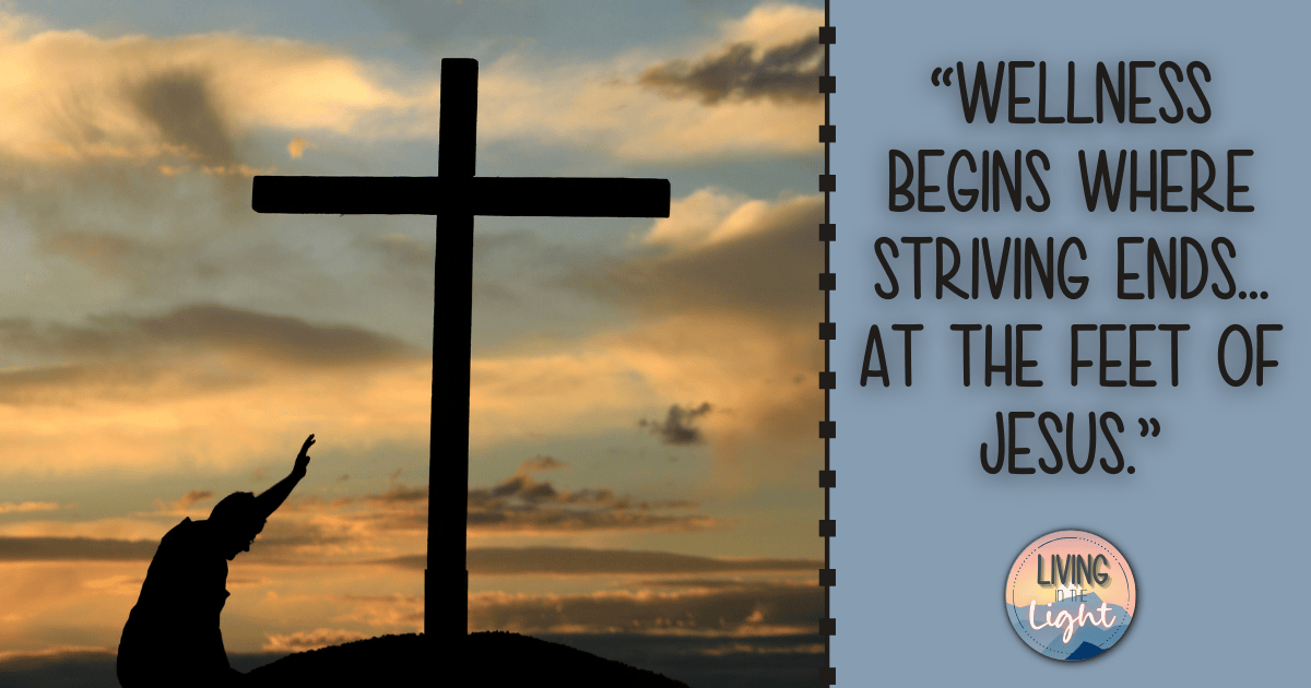Silhouette of a person kneeling at the foot of a cross during sunset with the quote, ‘Wellness begins where striving ends… at the feet of Jesus.’