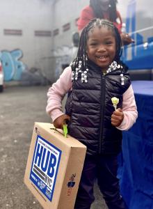 a little girl holds a donated box from NYDS.
