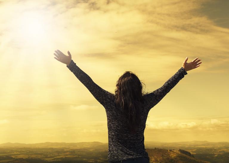 Woman worshiping in a sunrise