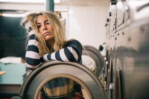 Woman in launderette clearly struggling with chronic pain and or tiredness
