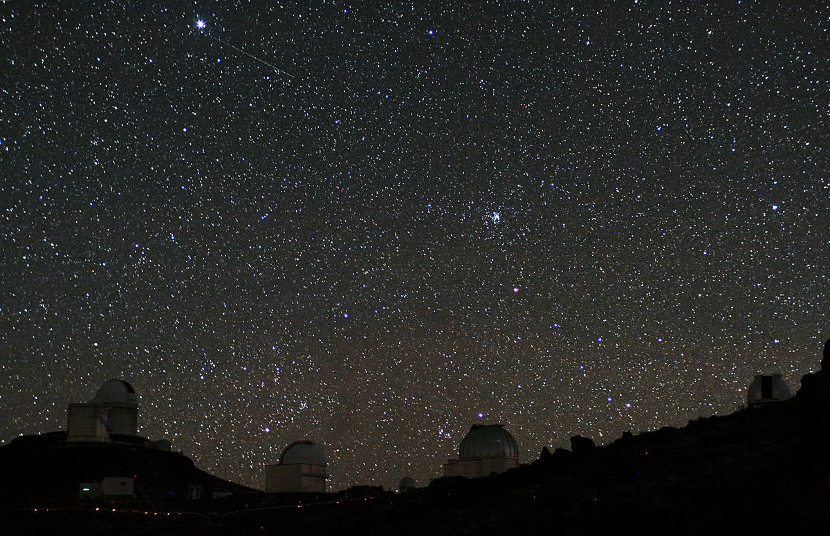 Starry night sky with two astronomical observatories in the foreground.