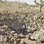 Make Way Partners staff members stand in bomb crater - Nuba - Copy