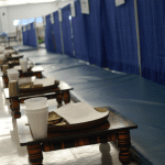 Individual tables and thali platters await the designated community members who will break their fast for the Parna celebration