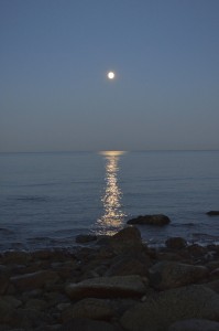 Full moon over the ocean and a rocky beach