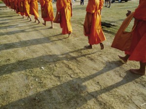 jodi-cobb-buddhist-monks-walk-single-file-down-a-dirt-road