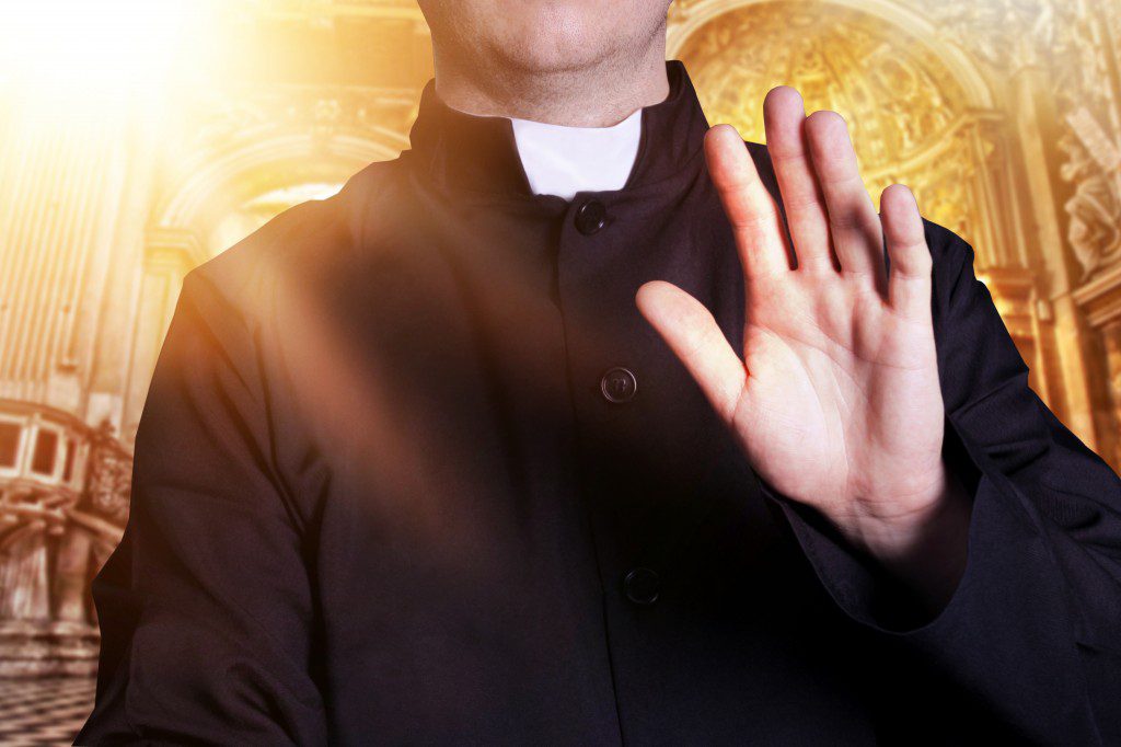 The priest at the church with raised hand