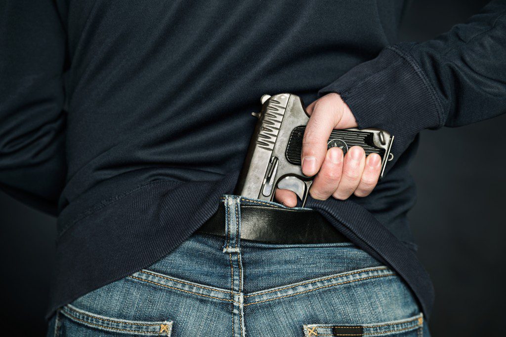 A person is hiding a handgun under the denim belt.