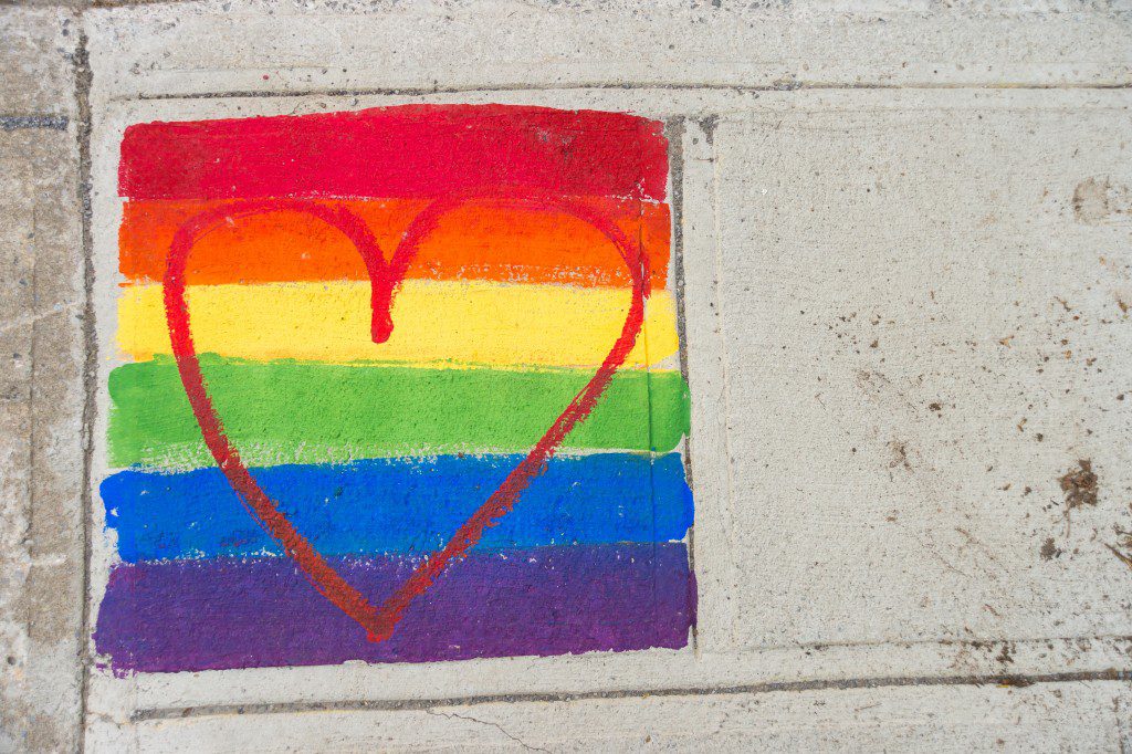 Gay rainbow flag and red heart painted on a sidewalk