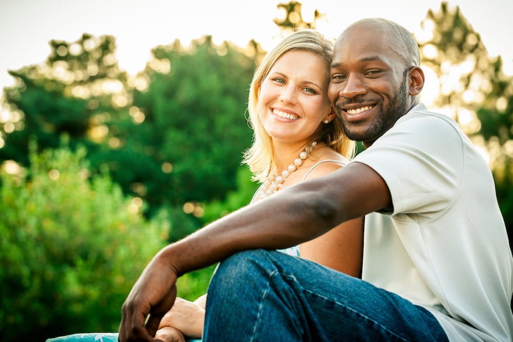 Beautiful mixed race couple or friends sitting at a park in the summer