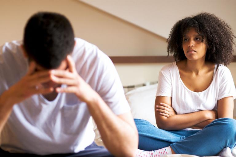 Frustrated couple sitting on bed