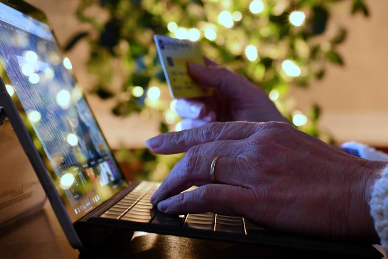 Woman's hands holding a credit card while typing on a computer keyboard