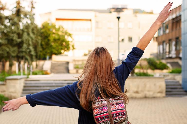 Teen girl walking down street wearing backpack