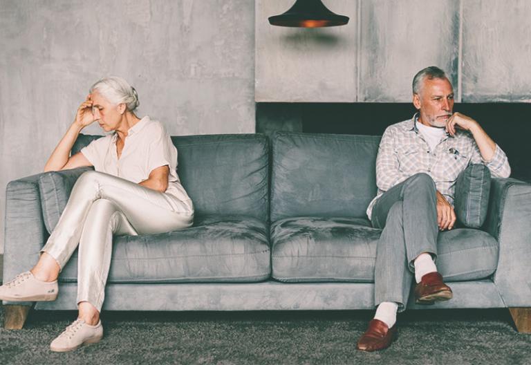 Unhappy couple on opposite edges of sofa - When You Tease Your Husband, It’s Really No Joke