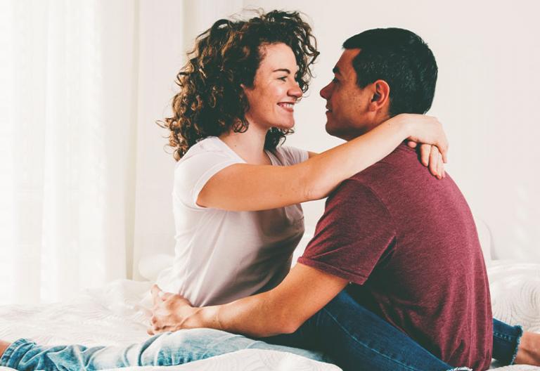 Happy couple embracing on bed - When You Tease Your Husband, It’s Really No Joke