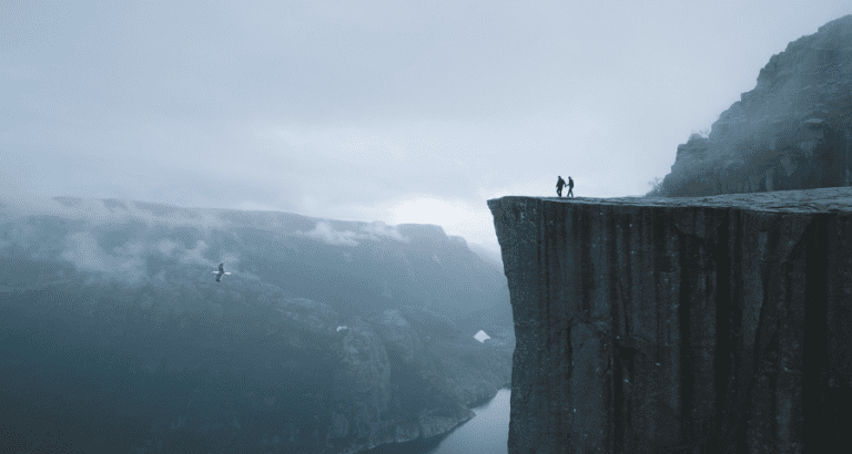 Two people standing at a mountain cliff