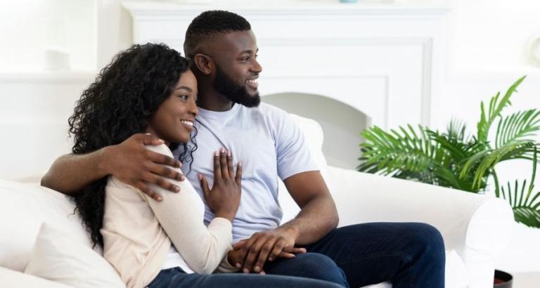 African American couple cuddle on the sofa