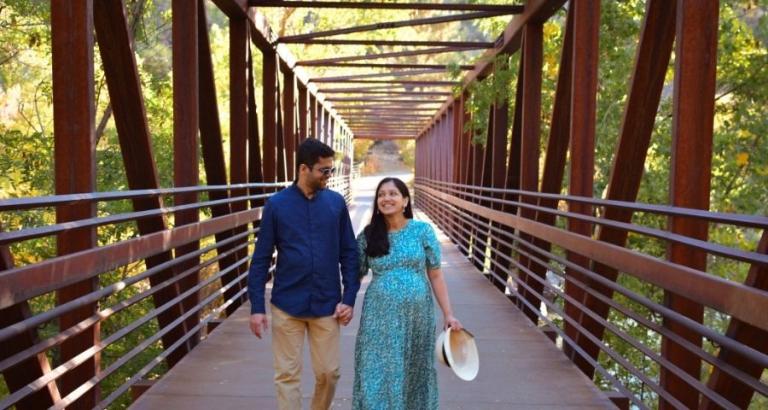Charming couple hold hands as they walk across a bridge