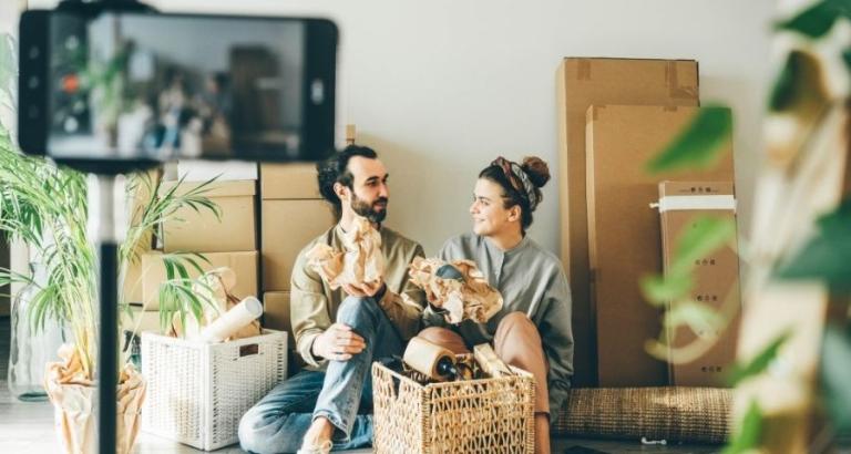 Young couple sits on the floor of their home as they unpack boxes