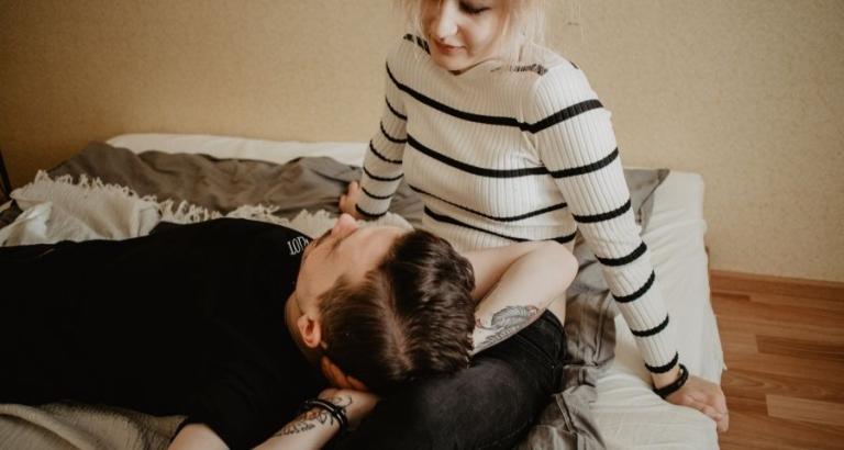 A young couple sit on a bed while having a serious conversation