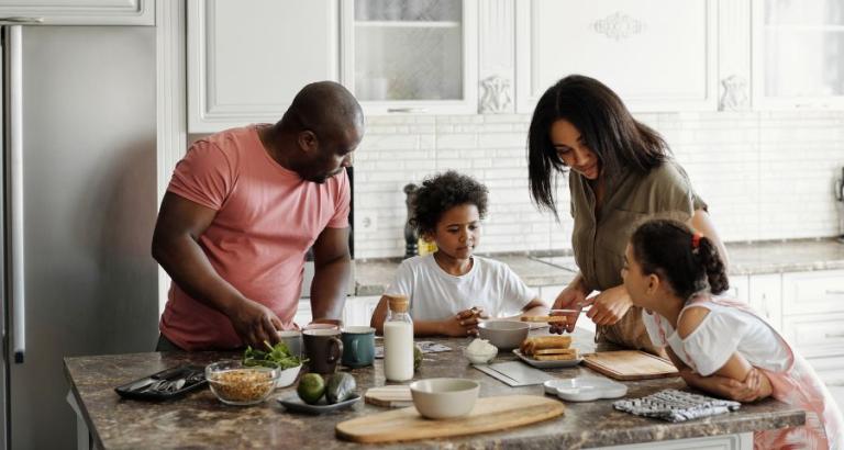A happy family prepares a meal in their kitchen