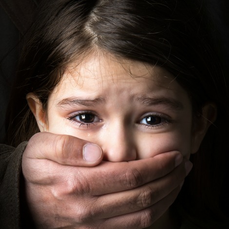 Scared young girl with an adult man's hand covering her mouth