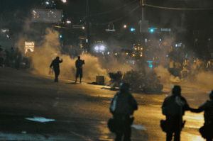 Police officers using tear gas during the first wave of the Ferguson unrest. Source: Wikimedia Commons.