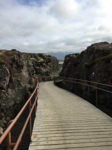 Image: two cliffs with a wooden walkway between them.