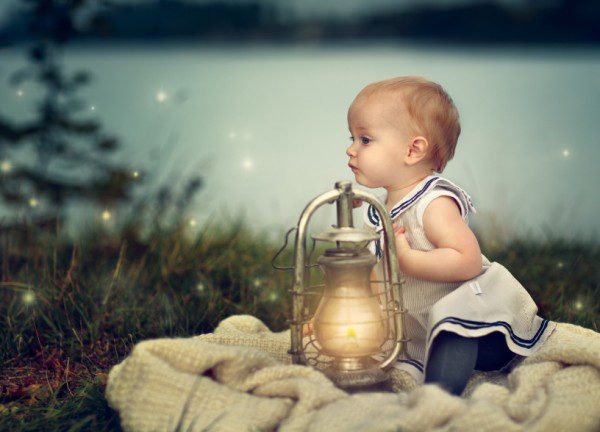 Portrait of a small baby girl at a Lake in the evening with glowing lantern