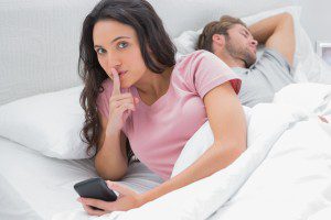 woman in bed secret on phone