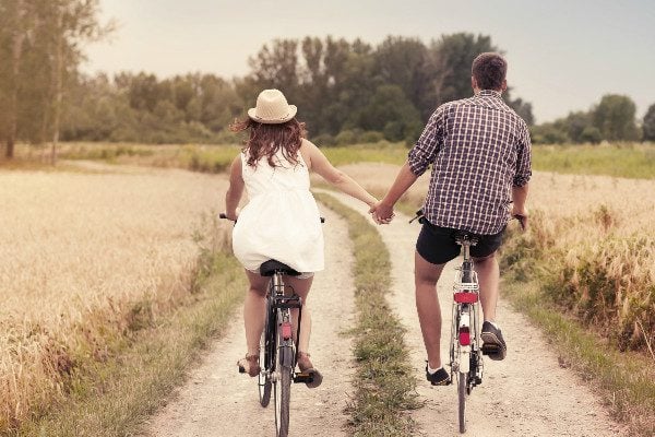 couple on bikes holding hands