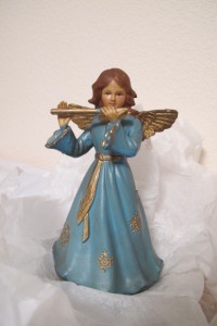 A plastic angel wearing a blue gown and playing a golden flute awaits placement at the top of our Christmas tree. Photo by Barbara Newhall
