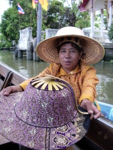 A saleswoman rows out to a tourist boat in Bangkok to offer a collapsible hat to wear in the sun. Photo by Barbara Newhall