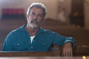 A bearded man sits in a pew.