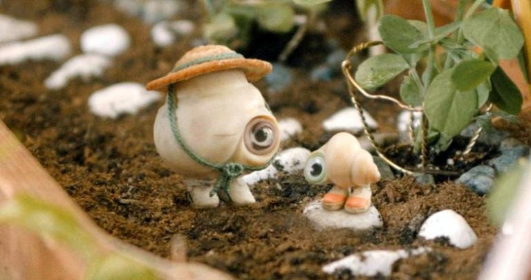 Two anthropomorphic shells stand in a miniature garden.