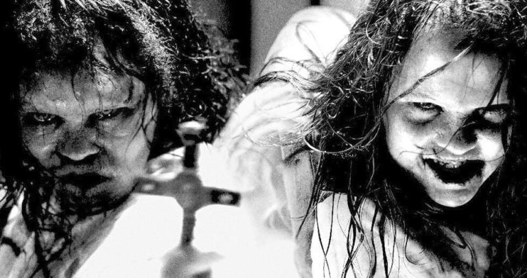 Two girls in demonic-possession makeup grimace at a crucifix.