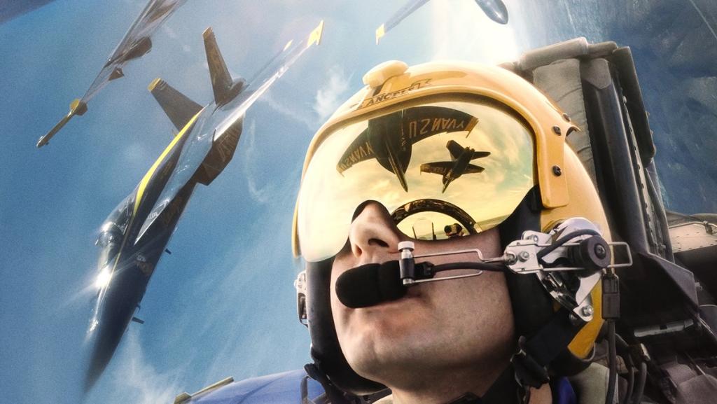 A Navy fighter pilot looks at other planes directly above and around him.