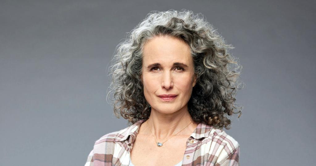 A woman with curly silver hair, wearing a plaid shirt.