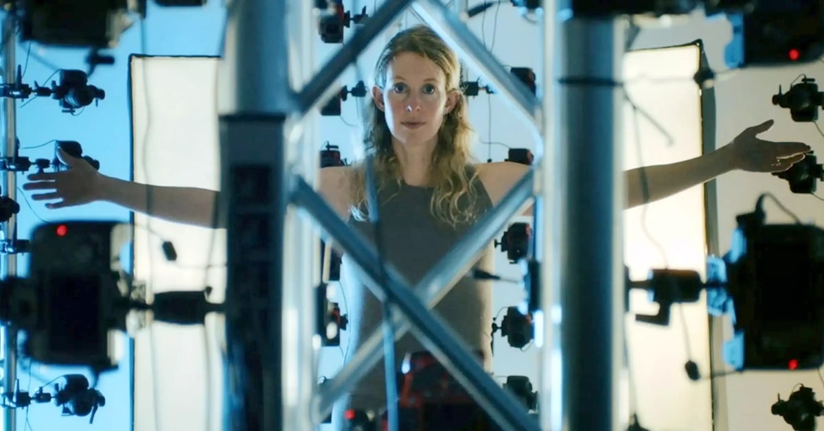 Convicted fraudster Elizabeth Holmes stands in side a batter of cameras.