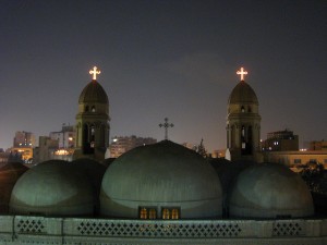 three-domed Coptic church with crosses on top lit up at night