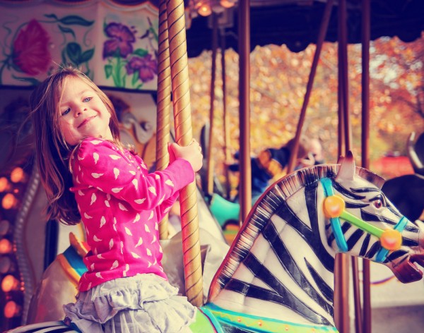 Young girl riding a carousel zebra