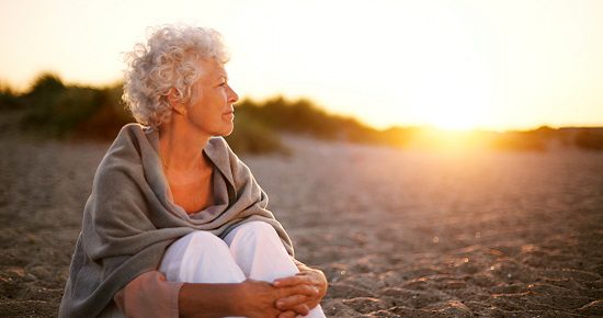 Woman sitting at sunset 550x290