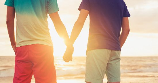 men holding hands at sunset 550x290