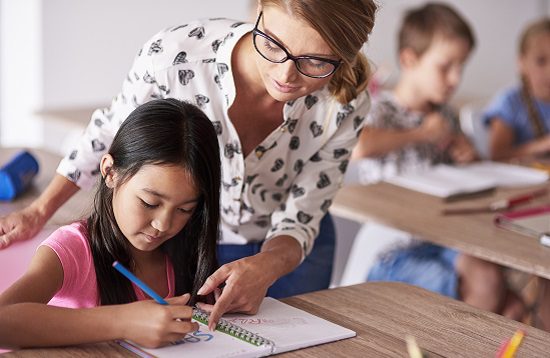 Teacher helping girl in homework