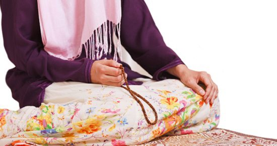 Young muslim girl with rosary praying on white background
