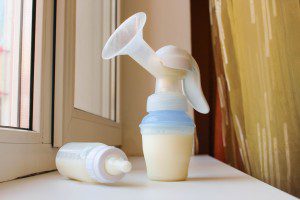 Breast pump and bottle of milk on the windowsill