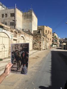 Our guide holds up a picture of this street in Hebron before the Israeli occupation. You can see the deserted street that exists now.